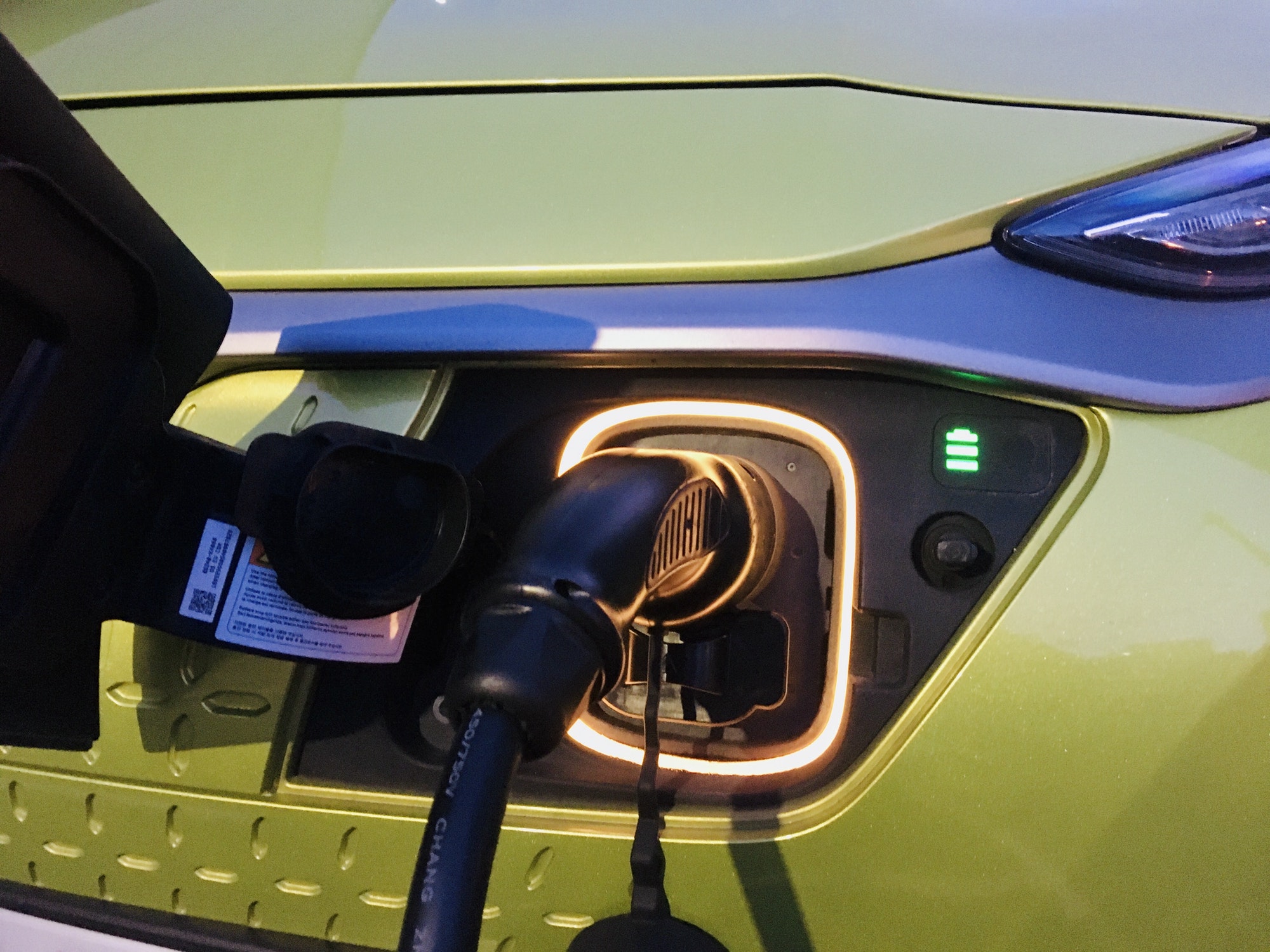 Green electric car on the charger close up